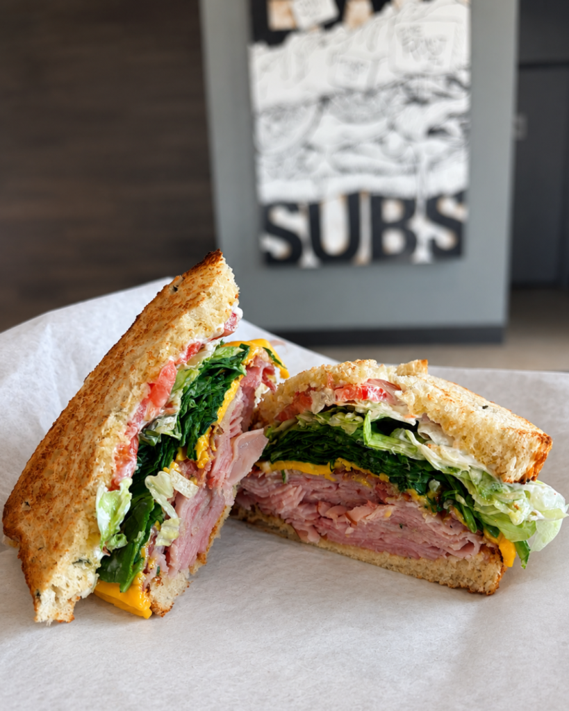 Sliced Toasted Ham Sub Sandwich Layered with Lettuce, Cheese, and Tomato Served on Deli Paper | O-Daddy's Brick Oven Sandwiches