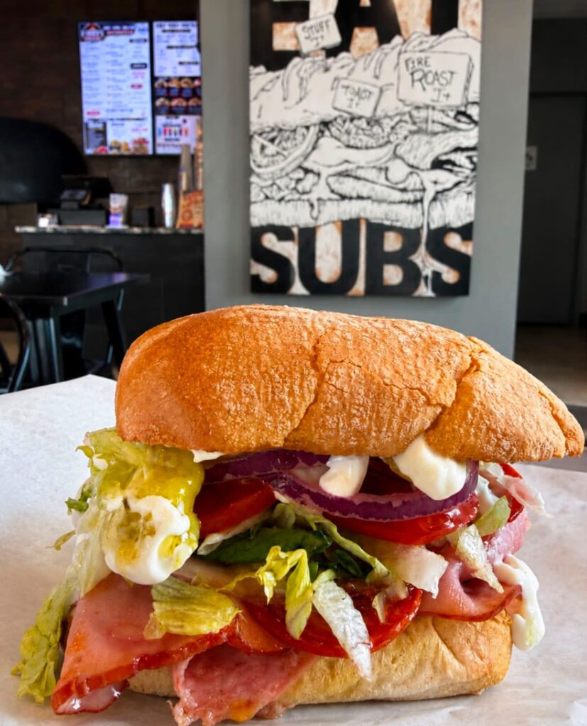 Toasted Italian deli sub sandwich loaded with sliced meats, red onions, tomatoes, lettuce, and mayonnaise inside O-Daddy's restaurant.