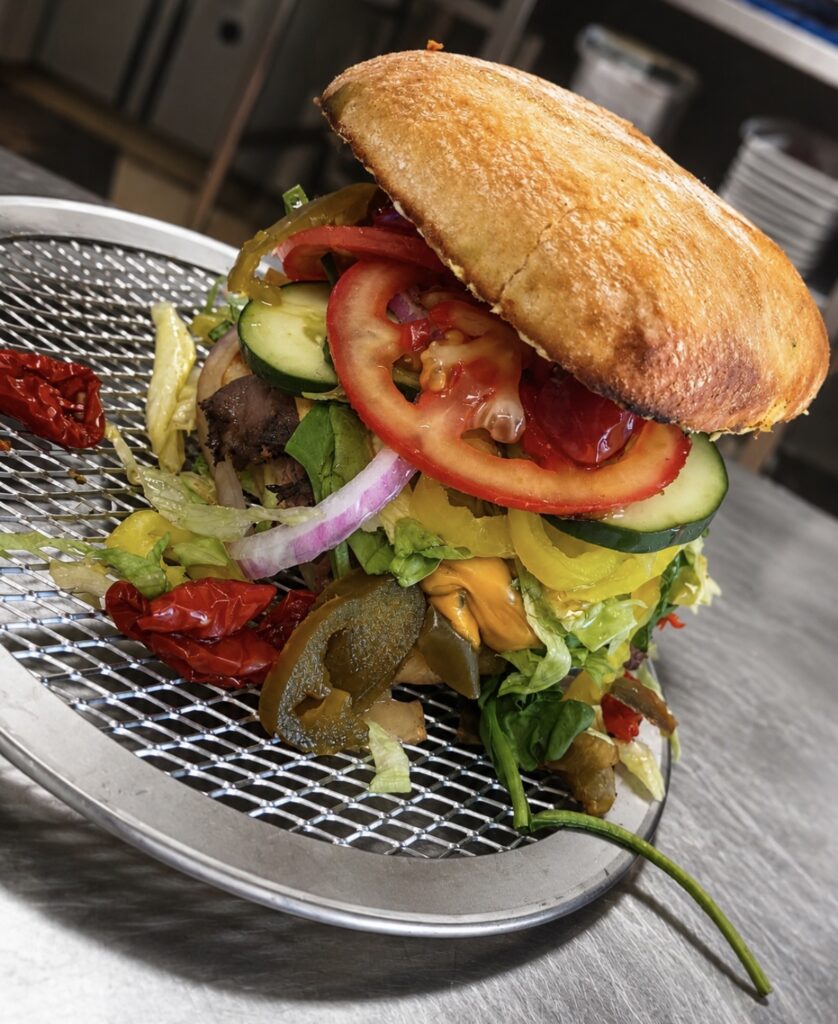Freshly Prepared Gourmet Specialty Sandwich Loaded with Sliced Tomatoes, Red Onions, Cucumbers, and Peppers on Toasted Artisan Bread | O-Daddy's Brick Oven Sandwiches