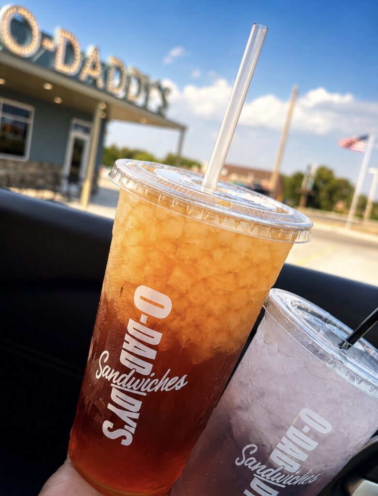 Clear Plastic Cups Filled with O-Daddy's Iced Tea and Crushed Ice in Front of The Restaurant Exterior | O-Daddy's Brick Oven Sandwiches