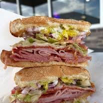 Stacked Cross-Section of A Toasted Sub Sandwich with Layered Deli Meats, Lettuce, Red Onions, and Peppers on Deli Paper | O-Daddy's Brick Oven Sandwiches
